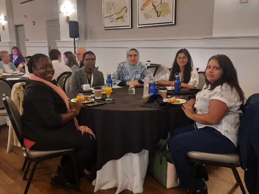 A group of conference goers sit around a round table smiling