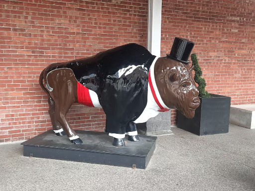 A cute painted statue of a Buffalo wearing a tuxedo and top hat