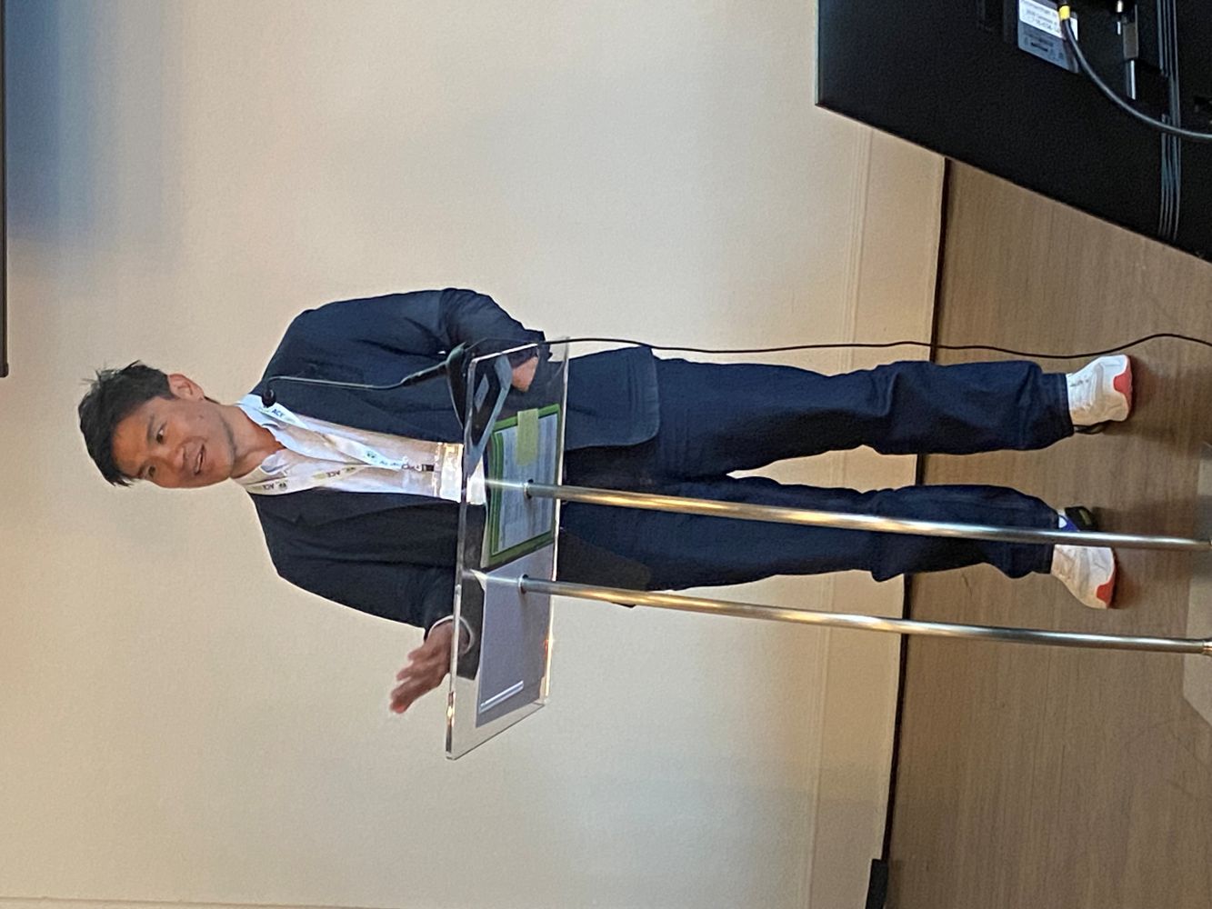 The Early Career Award recipient speaks from a metal and glass podium